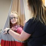 Therapist assists a girl in a sling